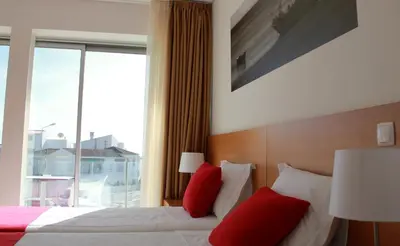a bedroom with a bed with red pillows and a window at Casa Praia Mar in Salema