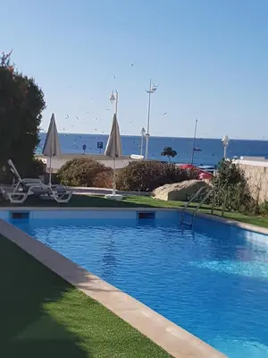 a swimming pool with a slide and umbrellas and the ocean at Casa Praia Mar in Salema