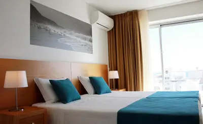 a bedroom with a bed with blue pillows and a window at Casa Praia Mar in Salema