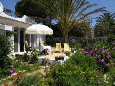 a garden with chairs and an umbrella and some flowers at VIVENDA JOHANNA in Lagos