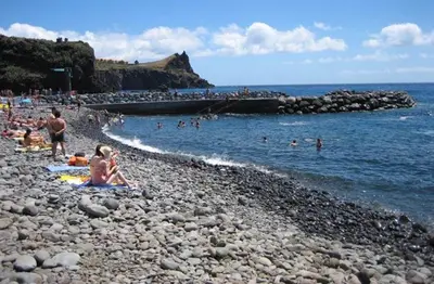 a group of people sitting on a rocky beach at Andrade Blue in Caniço