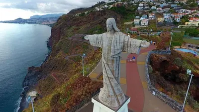 a statue of a christ the redeemer next to the ocean at Andrade Blue in Caniço