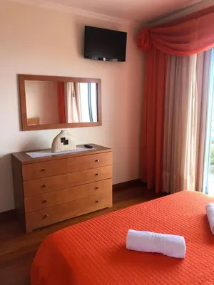 a bedroom with a bed and a dresser with a mirror at Andrade Blue in Caniço