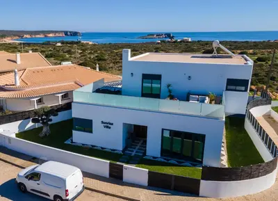 a white house with a car parked in front of it at Sunrise Villa in Sagres