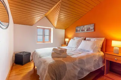 a bedroom with a large bed with an orange wall at Refúgio do Lourinho in Funchal
