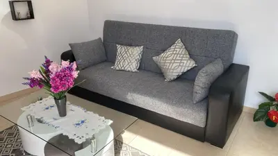 a living room with a couch and a table with flowers at SLICE OF PONTA DO SOL- GROUND FLOOR- SEA VIEW in Ponta do Sol