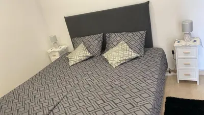 a bed with a black and gray comforter and two pillows at SLICE OF PONTA DO SOL- GROUND FLOOR- SEA VIEW in Ponta do Sol