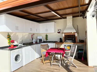 a kitchen with white cabinets and a table and chairs at SLICE OF PONTA DO SOL- GROUND FLOOR- SEA VIEW in Ponta do Sol
