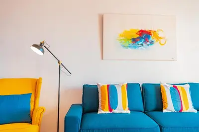 a blue couch with colorful pillows next to a lamp at FLH Funchal Ocean View with Pool in Funchal