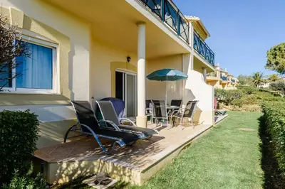 a house with chairs and an umbrella on a patio at Boavista Golf Resort- Fairviews Villa in Lagos