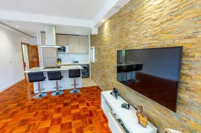 a kitchen with a large flat screen tv on a brick wall at Sea Breeze II in Caniço