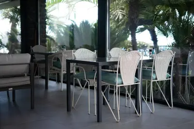 a table and chairs in a restaurant with palm trees at Casa das Proteas in São Jorge
