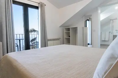 a white bedroom with a large bed and a balcony at Casa das Proteas in São Jorge