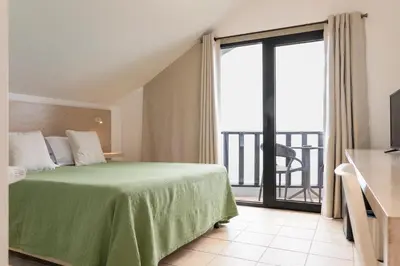 a bedroom with a green bed and a balcony at Casa das Proteas in São Jorge