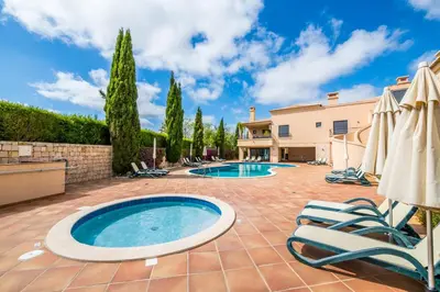 a patio with a swimming pool and two lawn chairs and umbrellas at Mar da Luz Resort in Luz