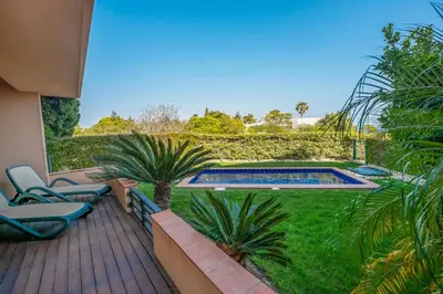 a deck with chairs and a swimming pool in a yard at Mar da Luz Resort in Luz
