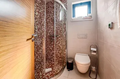 a bathroom with a shower with a toilet and a window at Mar da Luz Resort in Luz