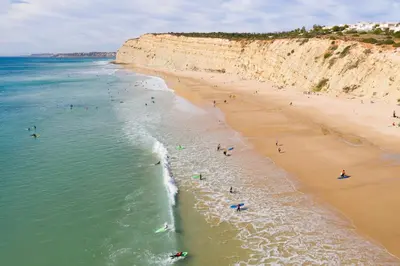 a group of people swimming in the ocean on a beach at Porto de Mós 72 by Destination Algarve in Lagos
