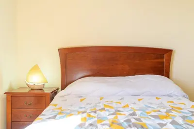 a bed with a wooden headboard and a lamp on a night stand at Madeira House in Calheta