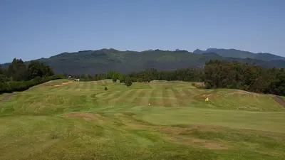 a view of a golf course with mountains in the background at Quinta das Colmeias in Santo da Serra