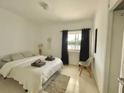 a white bedroom with a bed and a window at Casa da praia in Aljezur