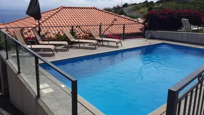 a swimming pool with chairs and a fence at Paraiso das Flores in Estreito da Calheta