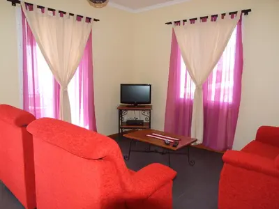a living room with two red chairs and a tv at Paraiso das Flores in Estreito da Calheta