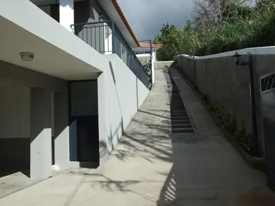 a sidewalk next to a building with a fence at Paraiso das Flores in Estreito da Calheta