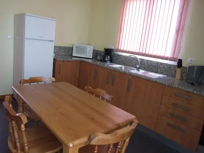 a kitchen with a wooden table and a refrigerator at Paraiso das Flores in Estreito da Calheta