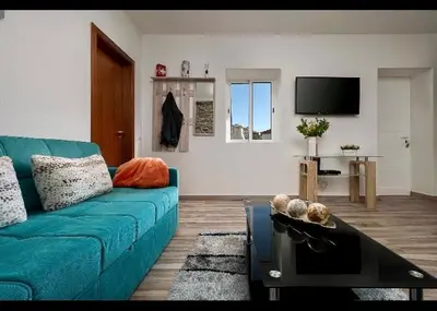 a living room with a blue couch and a tv at Casa Tiana Madeira in Ponta do Sol