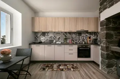 a kitchen with white cabinets and a table and a fireplace at Casa Tiana Madeira in Ponta do Sol