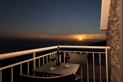 a table with two glasses of wine on a balcony at Casa Tiana Madeira in Ponta do Sol
