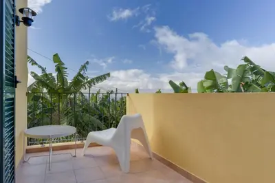 a balcony with a white chair and a yellow wall at Casa D`Avó Celina in Funchal