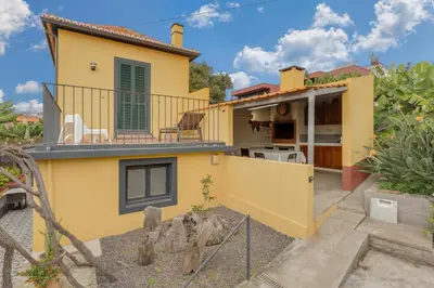 a yellow house with a balcony and a yard at Casa D`Avó Celina in Funchal