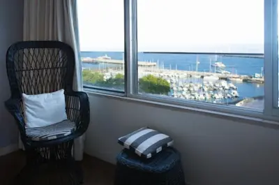 a room with a chair and a window with a view of a harbor at Apartment W Stunning View - MARINA - Free Parking & AC in Funchal