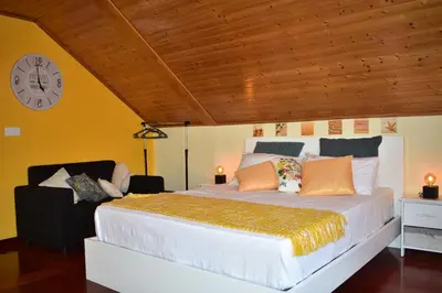 a bedroom with a large bed with a clock on the wall at Casa do Avô Ladeira in Estreito da Calheta