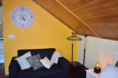 a black couch in a room with a clock on a wall at Casa do Avô Ladeira in Estreito da Calheta