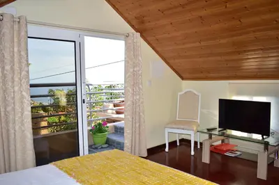 a bedroom with a bed and a television and a balcony at Casa do Avô Ladeira in Estreito da Calheta