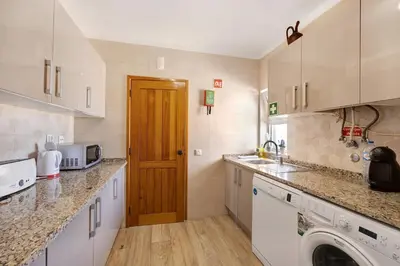 a kitchen with white cabinets and a washer and dryer at Apartamento Navegador in Sagres