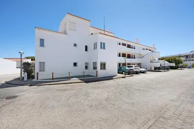 a white building with cars parked in a parking lot at Apartamento Navegador in Sagres