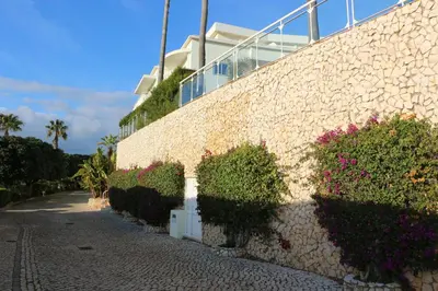 a stone wall with bushes and flowers next to a building at Lagos 61 in Lagos