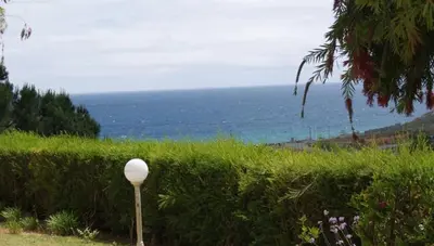 a pole in the grass with the ocean in the background at Lagos Marc & Cathy in Lagos