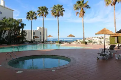 a swimming pool with palm trees and a beach at Lagos Marc & Cathy in Lagos