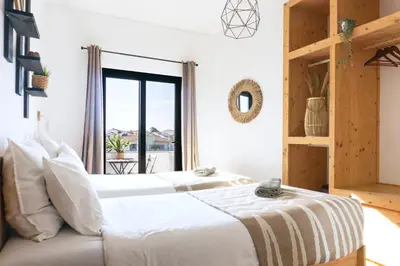 two beds in a room with a window at Algarve Surf Camp & Hostel Sagres in Sagres