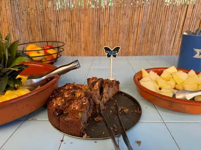 a plate with a piece of meat and a bowl of fruit at Algarve Surf Camp & Hostel Sagres in Sagres