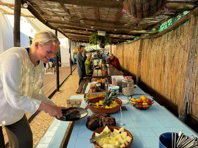 a woman standing in front of a table with food at Algarve Surf Camp & Hostel Sagres in Sagres