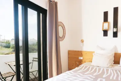 a bedroom with a bed and a view of a balcony at Algarve Surf Camp & Hostel Sagres in Sagres