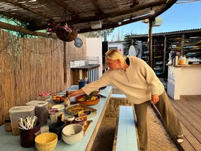 a woman preparing food on a table on a patio at Algarve Surf Camp & Hostel Sagres in Sagres