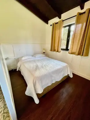 a bedroom with a white bed and a window at Palheiro do Avô in Santa Cruz