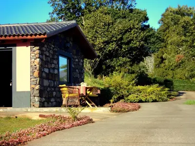 a stone building with a bench next to a driveway at Palheiro do Avô in Santa Cruz